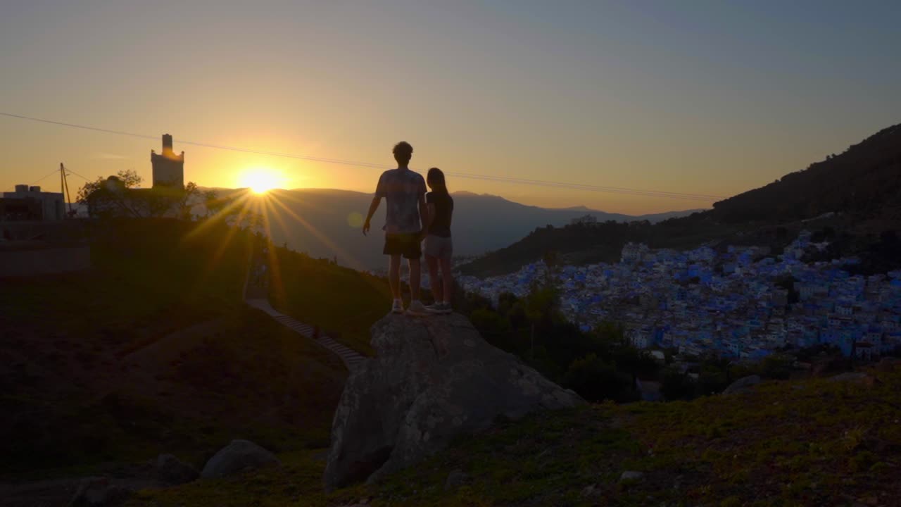 Pareja joven posando en el mirador de Chefchaouen al atardecer, momento romántico