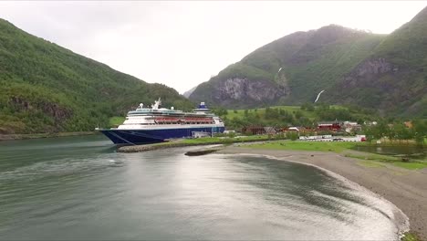 beautiful drone shot flying low towards a docked cruise ship in flam, norway