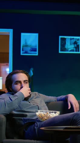 vertical video homeowner bored at home munching on snacks, watching tv
