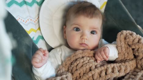 close-up of a pretty baby girl sitting in a swing covered with a plaid