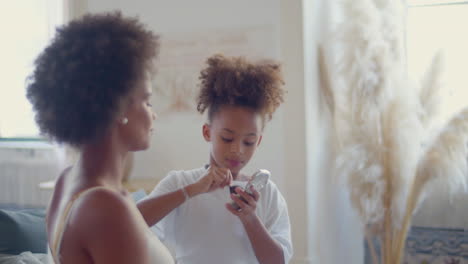 cute black girl doing make-up on her mother