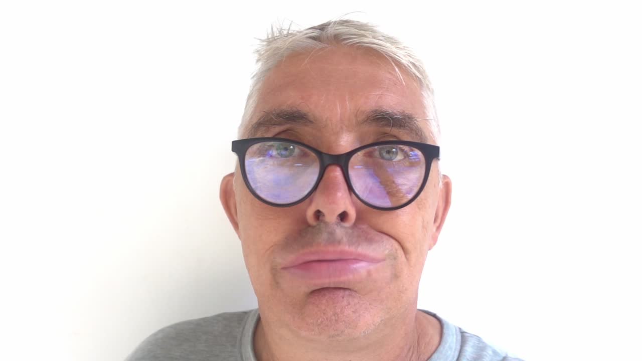 hombre blanco de mediana edad con gafas haciendo caras tontas en la cámara