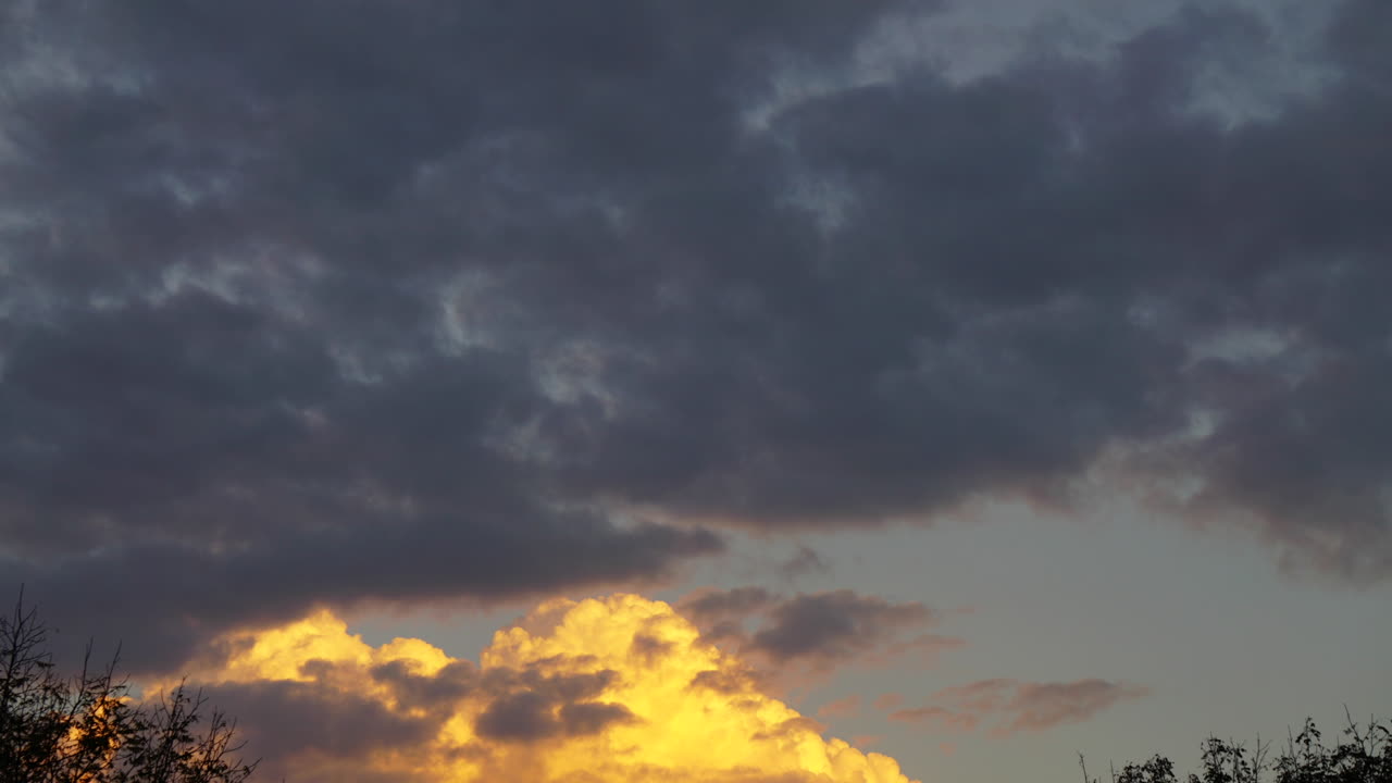 극적으로 조명된 누적 구름이 시간 경과 동작으로 하늘을 이동합니다.