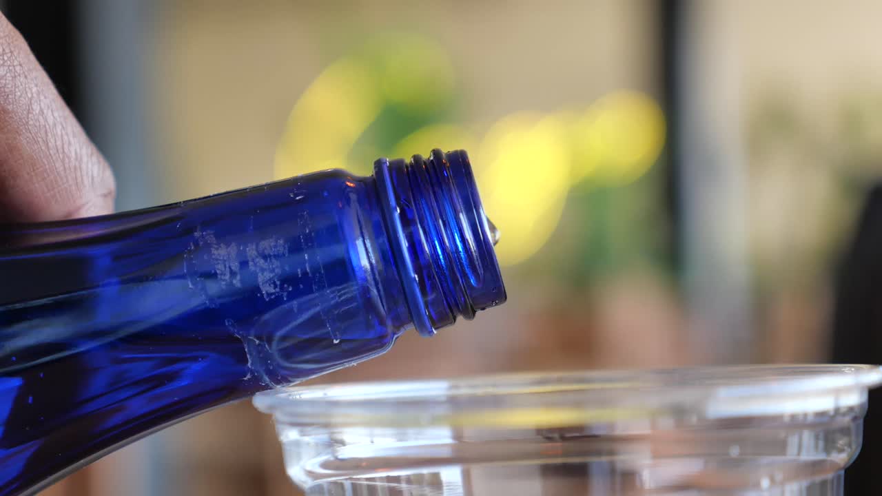 Pouring water from a blue bottle into a cup