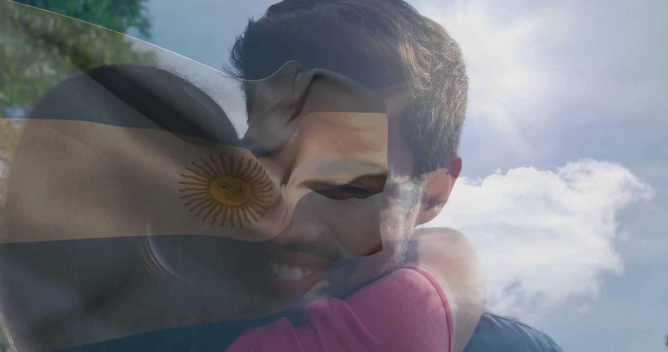Homem e mulher se abraçando no parque, começando a se beijar, com a bandeira argentina tremulando sobre os rostos, branding.