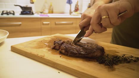 Person-Cutting-Medium-Done-A4-Wagyu-Steak-On-A-Wooden-Board-At-The-Kitchen