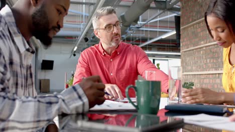 Diverse-colleagues-sitting-at-table-in-discussion-at-meeting-in-casual-office,-slow-motion