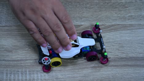 Una-Mano-Dejando-Caer-El-Tamiya-Mini-4wd-Cuatro-Veces-Sobre-La-Mesa,-Hobby,-Mini-4wd-Racing