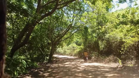 Disparo-En-Cámara-Lenta-Moviéndose-Por-Un-Pequeño-Y-Sinuoso-Camino-De-Tierra-Rodeado-De-árboles-Tropicales-En-El-Pequeño-Pueblo-De-Canguaretama-Cerca-De-Tibau-Do-Sul-Y-Natal-En-Rio-Grande-Do-Norte,-Brasil-En-Un-Día-De-Verano