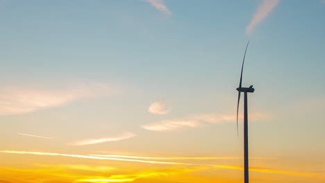 A-shooting-star-passing-over-an-active-windmill-of-Zlotoryja,-Poland-with-the-sunset-in-the-background---time-lapse