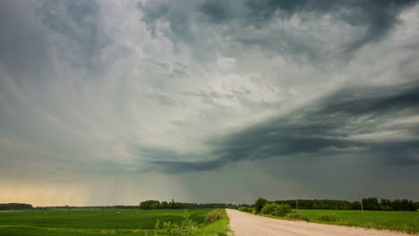 Dunkle-Regenwolken-über-Landstraße-Und-Grünem-Feld,-Dramatischer-Zeitraffer