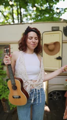 happy woman playing ukulele near camper van