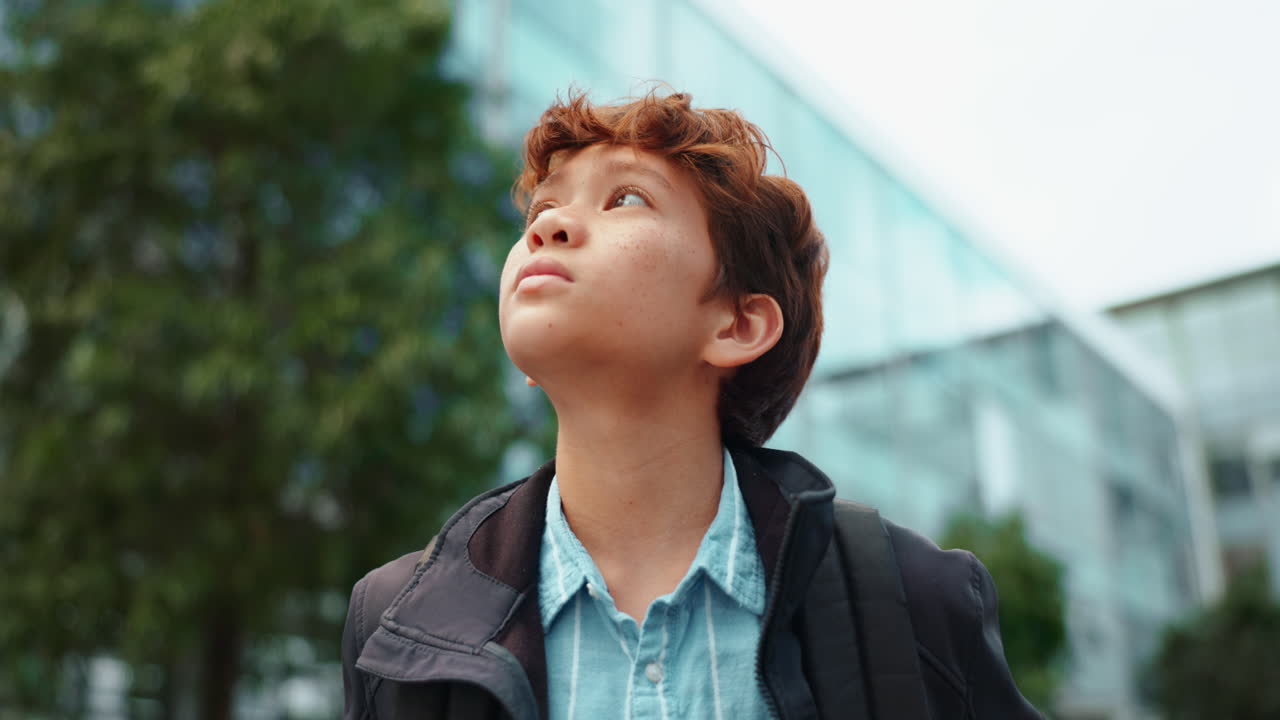 Boy looking up at modern building
