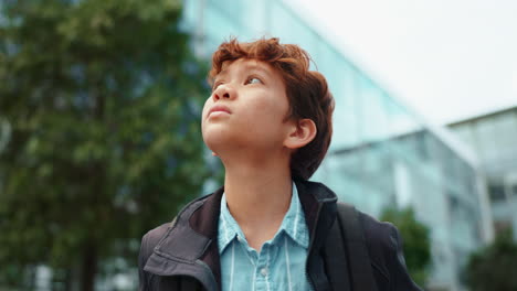 boy looking up at modern building