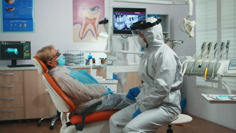 dentist in protection suit explaining dental surgery process