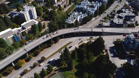 caída aérea sobre el puente del paso elevado junto al exuberante parque verde edificios de condominios de poca altura de verano de lujo por centros vip granville island bc canadá con vehículos de construcción estacionados en el hombro 5-5