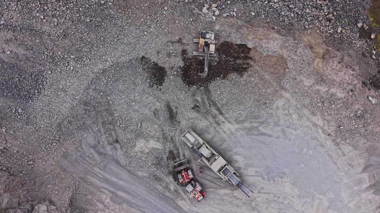 Heavy machinery works on gravel at a construction site in the afternoon