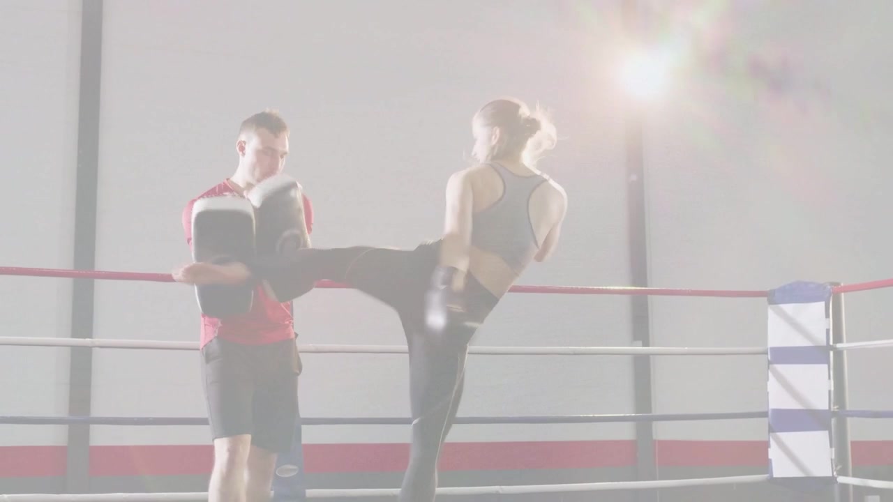 Allenatore che tiene i colpitori sul ring di pugilato e pugile che si muove, sferrando combinazioni, praticando il tempismo