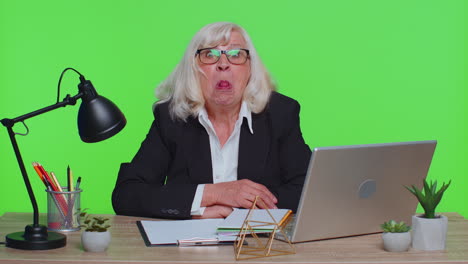 senior mature older office businesswoman working on laptop computer making funny face fooling around