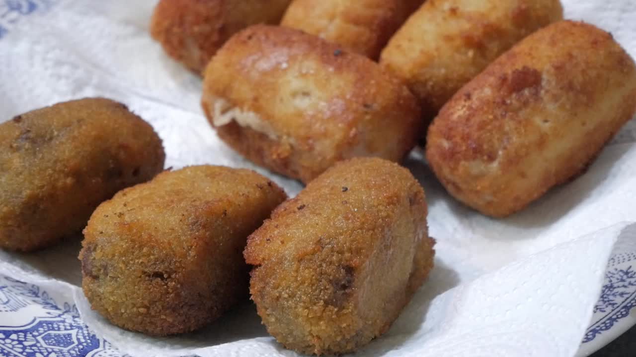 algunas croquetas en un plato que se sirven con pinzas