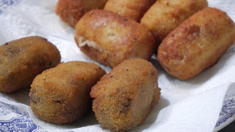 algunas croquetas en un plato que se sirven con pinzas