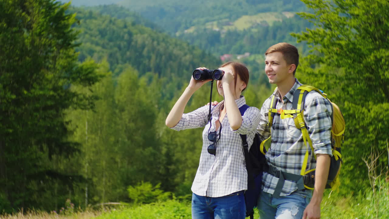 jóvenes turistas en el bosque mirando a través de binoculares
