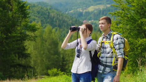 Jóvenes-Turistas-En-El-Bosque-Mirando-A-Través-De-Binoculares