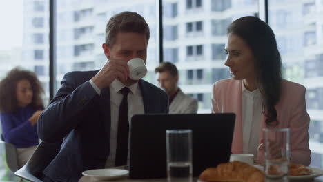 Two-professionals-discussing-business-project-at-laptop-online-meeting-in-cafe.