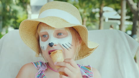 a girl with aquagrim on her face eats ice cream in the resort with a child concept