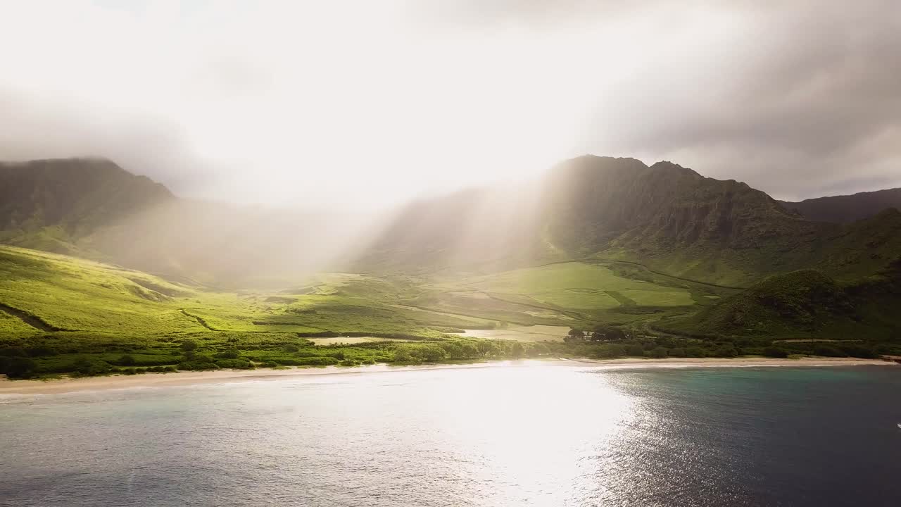 아름답고 극적인 4k 드론은 산 너머로 오는 태양 광선을 포착하고 마쿠아 해변에서 빛나고 있습니다.