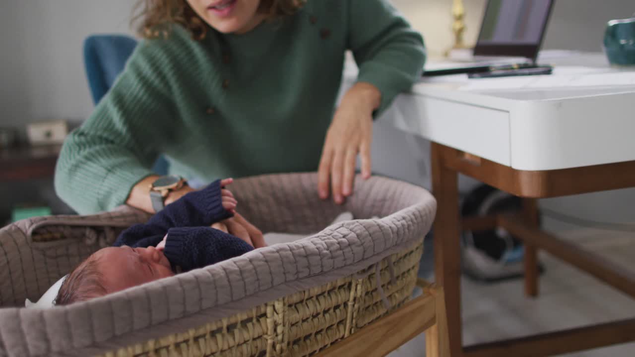 Video di madre caucasica che lavora al portatile da casa con neonato