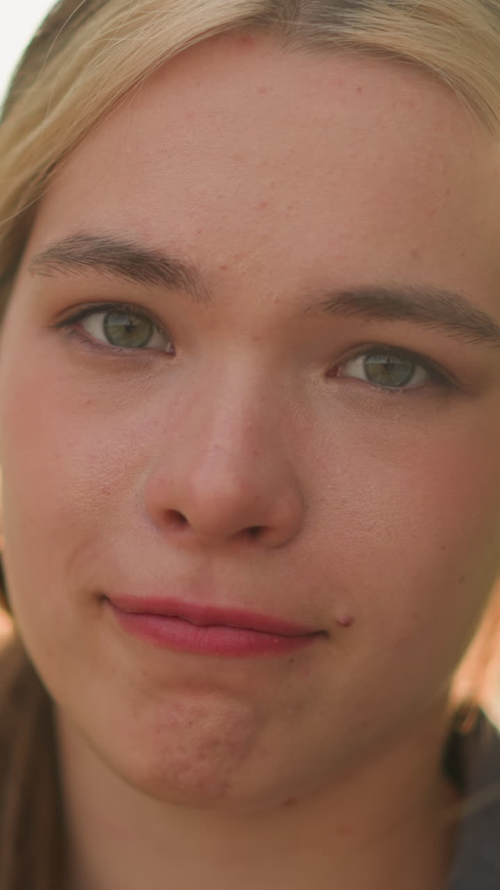 primer plano de una mujer mirando directamente a la cámara con una sonrisa sutil, la cálida luz del sol brillando suavemente por detrás, su rostro está iluminado en luz natural, con vegetación y un fondo borroso