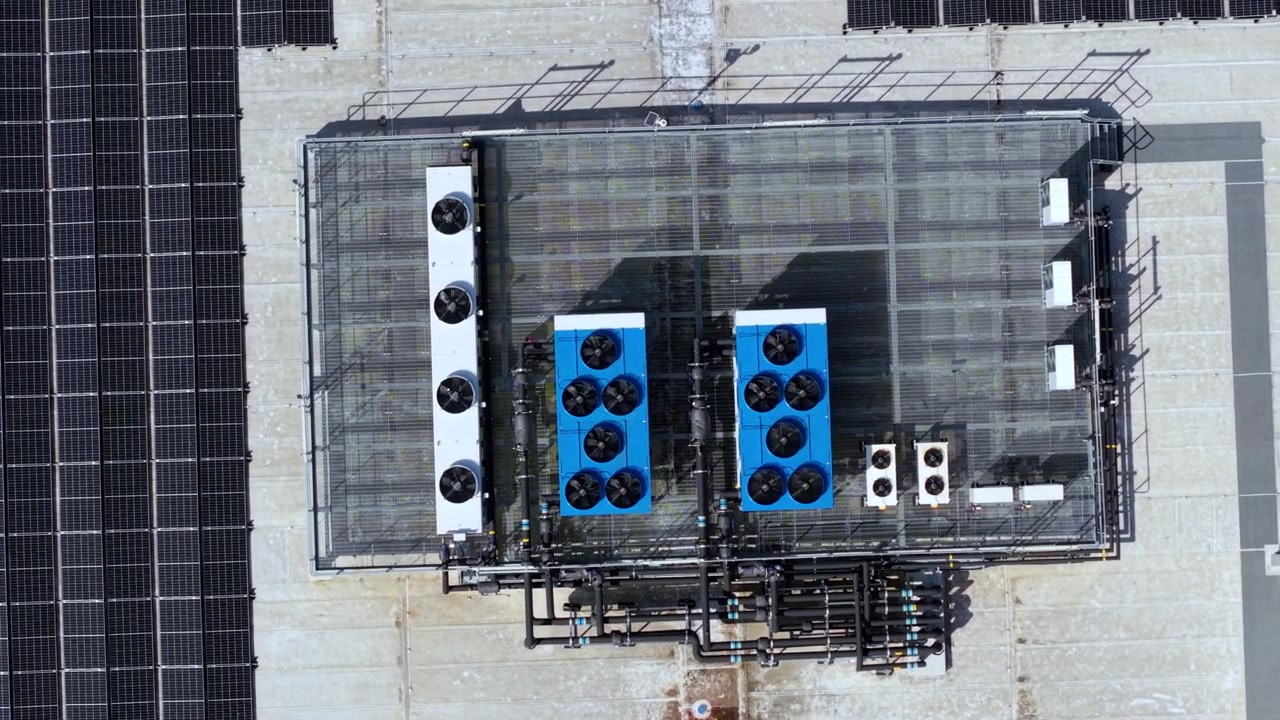 Close Up Aerial View of Industrial Rooftop Solar Panels Alongside Commercial HVAC Cooling Units