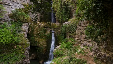 Aerial-view-of-the-exploration-through-the-caves-near-the-Waterfall-and-Mountain-River-in-Valbona,-Albania