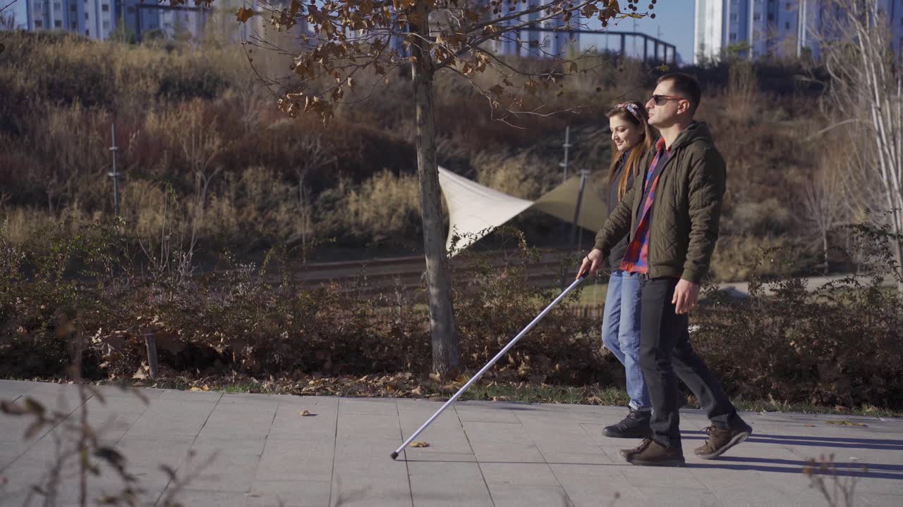 hombre ciego caminando por el parque con su esposa en otoño.
