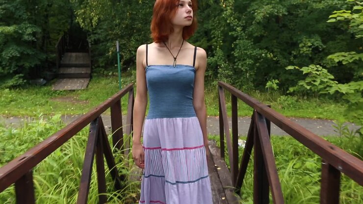 Donna che cammina a piedi nudi su un ponte di legno con un vestito a righe