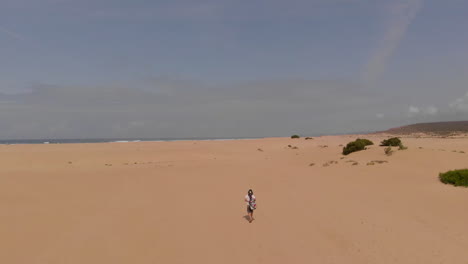 a lone girl walking on the sandy beach in summer at carrapateira, algarve, portugal. bordeira's beach- aerial drone shot