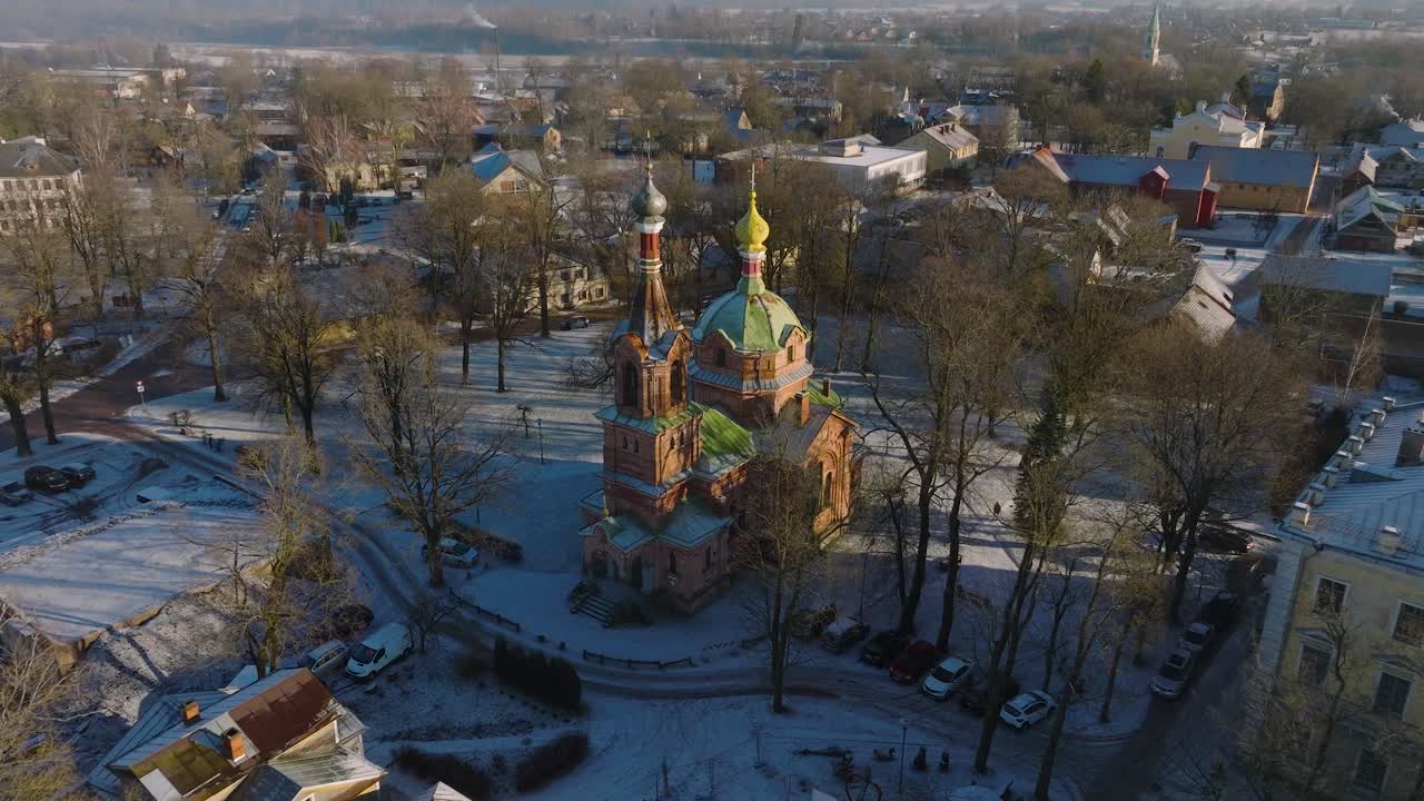 vista aérea del casco antiguo de kuldiga, casas con tejas rojas, iglesia ortodoxa, día soleado de invierno, destino de viaje, amplia toma de drone moviéndose hacia adelante, inclinándose hacia abajo