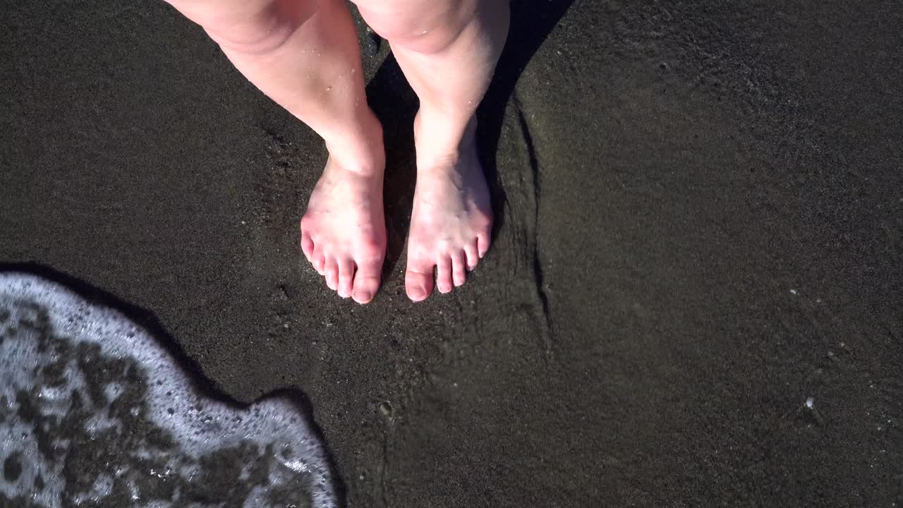 POV of a woman standing on a beach, calm waves hitting