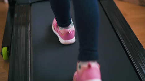 strong girl in bright sportswear walks along treadmill