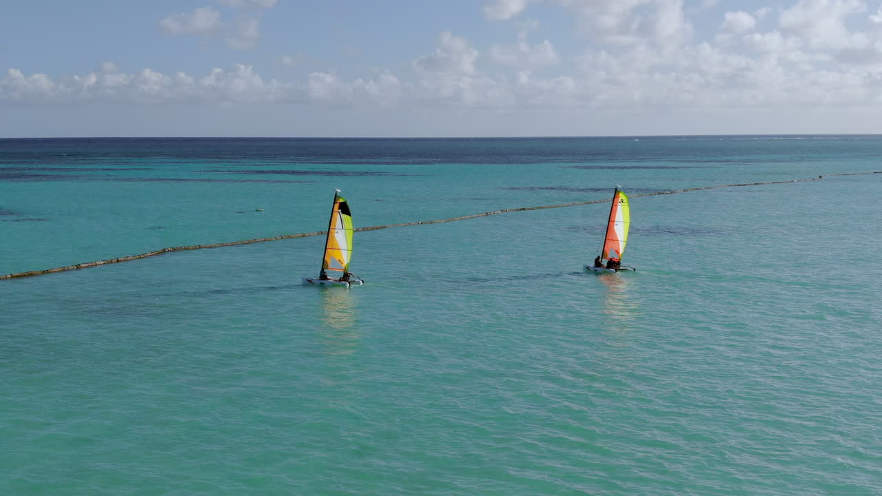 dos pequeños catamaranes navegan en el mar caribeño turquesa, diversión en deportes acuáticos y recreación en un paraíso tropical