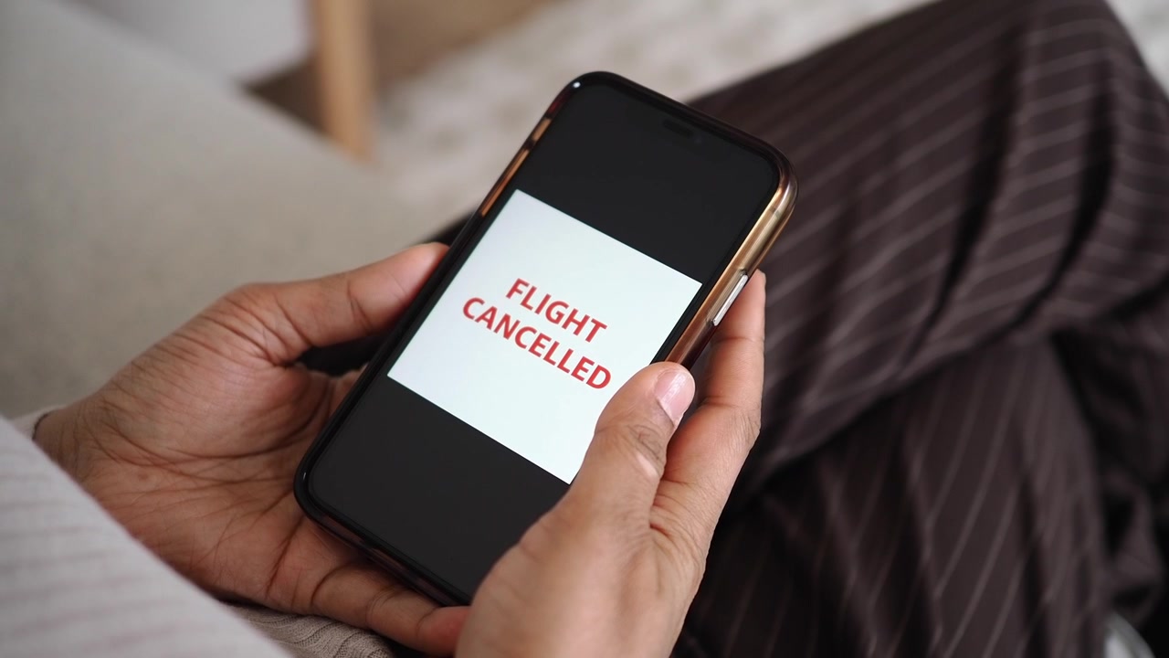 Person Holding Smartphone Displaying Flight Cancelled Notification