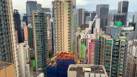 new building construction in hong kong surrounded by concrete jungle high rises