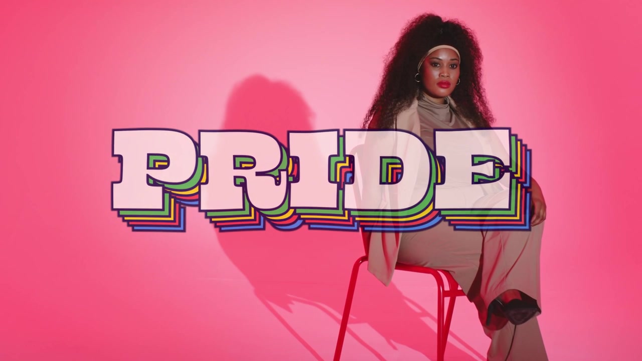 Kvinde poserer på rød stol til modeshoot, kameraet optager, med PRIDE-overlay der dækker den nederste halvdel