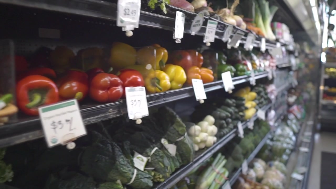 No supermercado: Movimento lento de câmera (dolly in) em frutas e vegetais no atraente mercado.