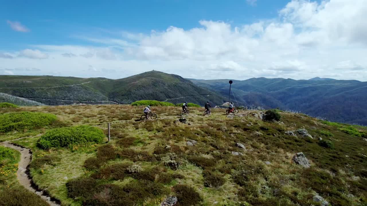 Vídeo de drone de 4 ciclistas de mountain bike alcançando o pico de uma montanha.