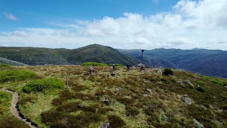 Drone-video-of-4-mountain-bikers-reaching-the-peak-of-a-mountain-top