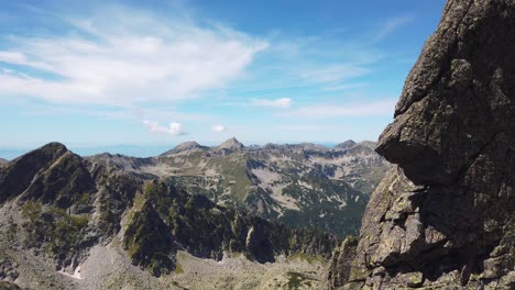 alpine rock phenomenon - a window in the rocks and an impressive massive shape. panoramic view from the guards in pirin mountain, bulgaria. sunny summer day. pan left