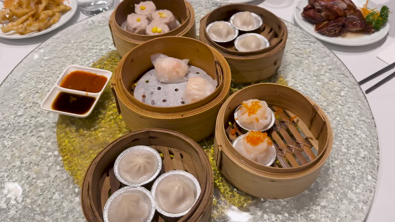 A variety of dim sum dishes presented on a rotating lazy Susan in a well-lit dining setting