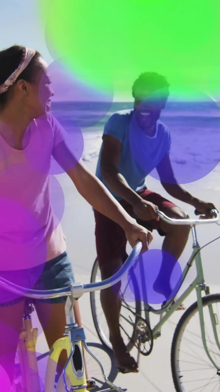 Colorful bokeh animation over people walking bicycles on beach